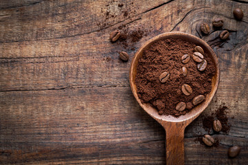 Obraz na płótnie Canvas Ground powder arabica coffee with coffee beans in a dark wooden spoon against rustic background. Flat lay with copy space for your text