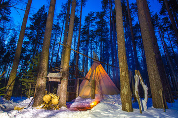 National Indian housing. Tipi in the evening forest. Winter overnight in the forest. Fire on the...