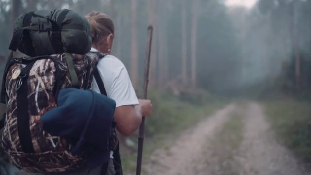 Way of Saint James pilgrim backpacker female going by the path through Eucalyptus forest  back view slow motion footage.