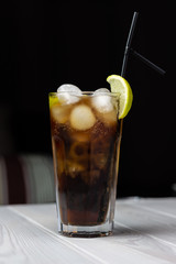 Alcoholic cocktail with a slice of lemon and ice is on the cafe table