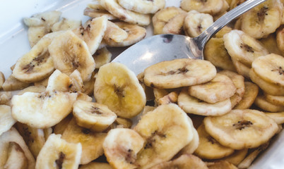 Banana chips in a white breakfast bowl with a spoon