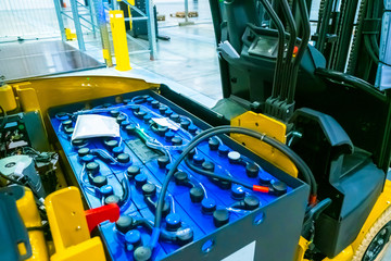 Fragment of a forklift. The battery of the truck. Warehouse storage. Automation of the storage process. Yellow forklift in the warehouse. Replacing batteries on a forklift.