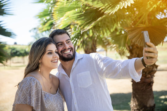 Beautiful couple making selfie photos with a cellphone on a sunny day in the park