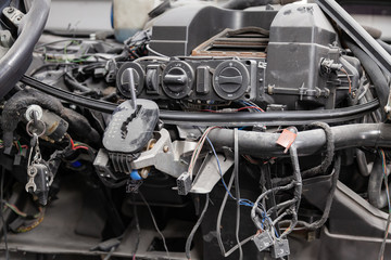 Car interior in the back of a van with a disassembled dashboard and view on shift gear and climate-control during preparation in a vehicle repair workshop. Auto service industry