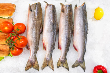Headless salmon on ice, garnished with vegetables. Storage fish in cold. Selling fresh red fish....