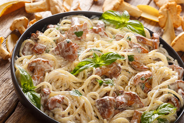 Delicious Spaghetti with fried chanterelle mushrooms in a creamy cheese sauce close-up on a plate. horizontal