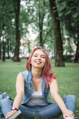 Obraz premium The girl with red hair in the park at a picnic reads a book