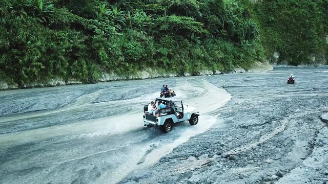 People in 4x4 and ATV off road vehicles driving through the rough terrain around Mt Pinatubo volcano in the Philippines. Drone shot