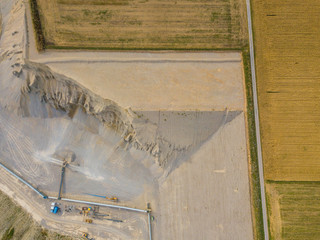 Aerial view of open cast gravel mine in Switzerland. Land grabbing for mining industry. Fields beside gravel quarry.