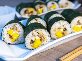 sushi rolls on a plate with mango white cheese and eel