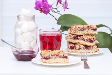 Homemade shortcrust berry pie with crumble on white background. Cherry jam, cherry compote or kissel, tasty cake.