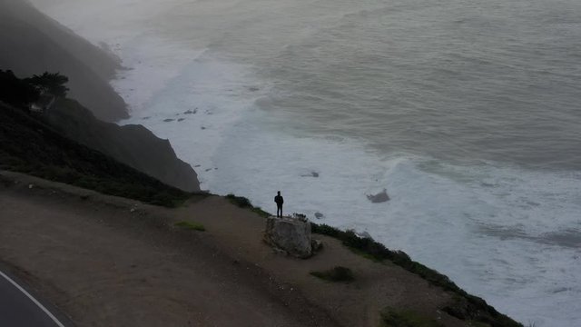 Aerial of man standing on rock in Big Sur California at sunrise