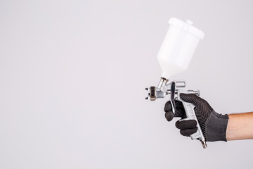 Hand and spray gun at work on white background