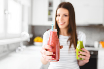 Close up of beautiful woman holding and offering red smoothie in jar.
