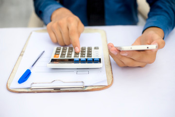 Finance person table's or workplace's close up a shot while he was doing some finance and loan-related work with cell phone, calculator and pages, and pen.