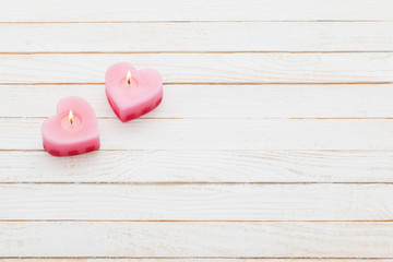 pink burning candles on white wooden background