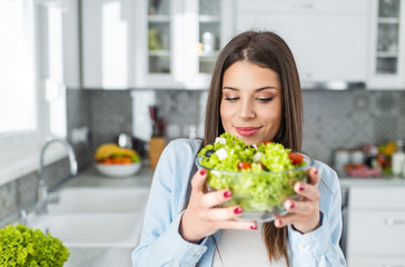 Portrait of young beautiful caucasian girl holding a glass bowl of salad.