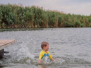 Fototapeta premium Two funny kids in swimsuits swim on an inflatable circle. boys are happy on holiday in village together. Summer day, river, swimming in water
