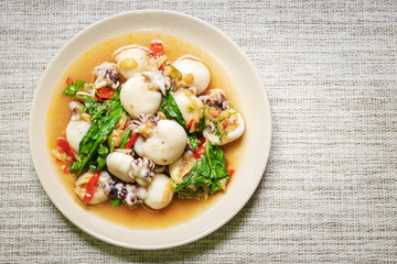 Stir fried Cuttlefish or Cuttlefish Rainbow with basil on table mat with copy space; top view. Thailand's popular dishes (Pad Ga Pow).