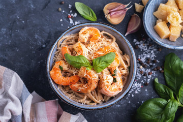 Pasta with shrimps in a plate, close-up, copy space, top view. Pasta cooking concept, ingredients and spices on a table with a dish.