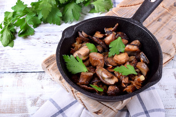 Roasted forest mushrooms topped with fresh parsley in a cast iron pan