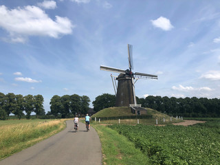 Tourists on a bicycle passing by a windmill