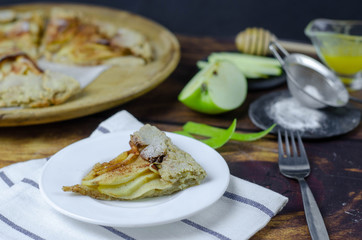 Piece of apple galette on the plate served with cinnamon and honey