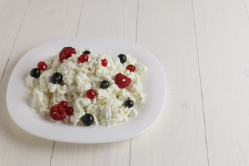 Plate with cottage cheese and fresh berries on wooden table