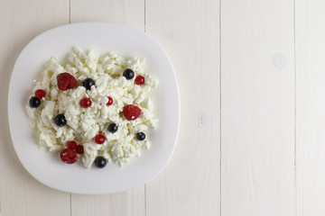 Plate with cottage cheese and fresh berries on wooden table