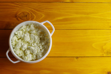 Bowl with cottage cheese on wooden table