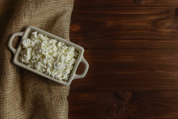Bowl with cottage cheese on wooden table