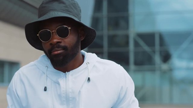 Portrait african american young attractive man wear sunglasses walk street smile sunlight sunset cellphone internet face outside technology businessmen black city mobile slow motion