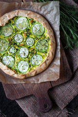 Homemade courgette and goat cheese pie on a dark rustic wooden board background
