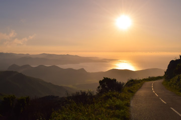 empty road in the mountains with sunset view to the ocean