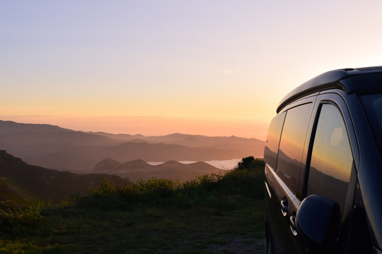Campervan in the mountains with stunning view to the sea in the sunset
