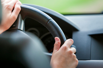 Woman hands on steering wheel driving a car.