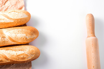 Freshly baked French baguettes on white wooden table.