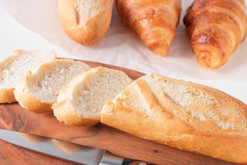 Freshly baked French baguettes on white wooden table.