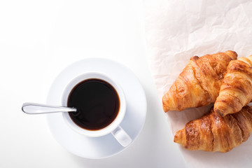 cup of black coffee and croissant on white