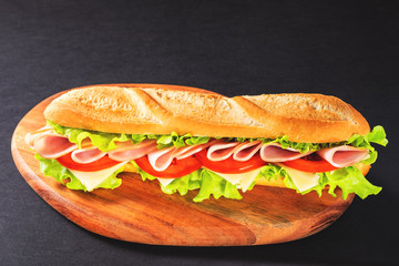 Big submarine sandwich with ham, cheese and salad