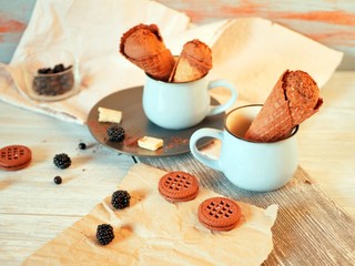  Chocolate ice cream in wafer cones, cookies, berries on a wooden table, dessert in the hot season, homemade treats