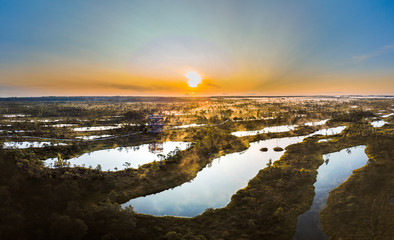 Warmly colored sunrise over a foggy swamp. Aerial view of stunning landscape at peat bog at Kemeri...