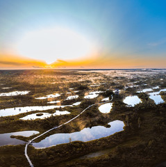 Warmly colored sunrise over a foggy swamp. Aerial view of stunning landscape at peat bog at Kemeri...