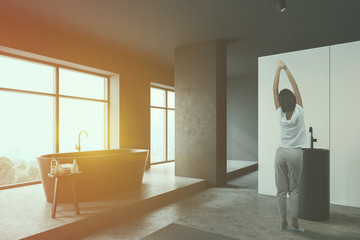Woman in white bathroom corner with tub and sink
