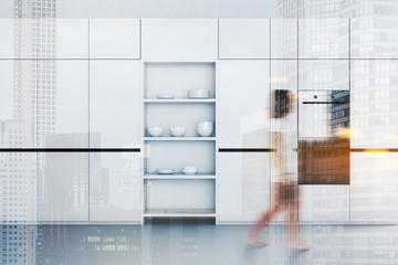 Girl waking in white kitchen with cupboards