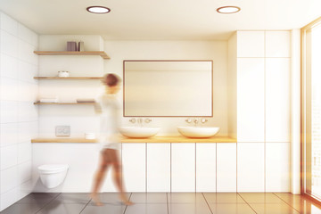 Woman walking in white bathroom with toilet