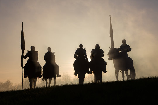 A group of medieval knights silhouetted against the sunset.