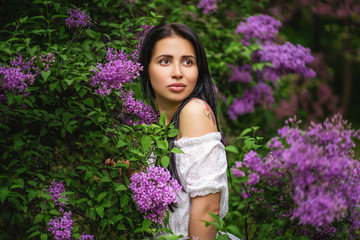 portrait of authentic girl in blooming bush with purple flowers