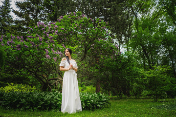 young woman with long dark hair posing near the tree with purple flowers.