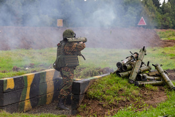 A soldier shoots a jet flame thrower into the field.